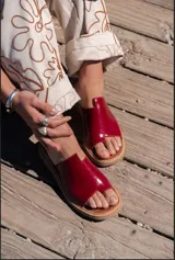 Sandalias rojas con base marrón y tira ancha que separa el dedo gordo del resto.