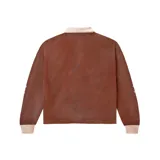 Camiseta de rugby de manga larga color marrón, con cuello polo en tono crema y cierre frontal de botones. Presenta múltiples estampados y bordados temáticos en el frente, incluyendo logotipos deportivos, motivos ecuestres y tipografía estilo universitario.