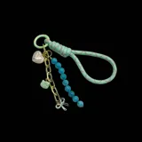 Colgante para cartera con cadena dorada y charms colgantes: frutilla roja, Hello Kitty rosa, cerezas con strass y cordón trenzado rosa.