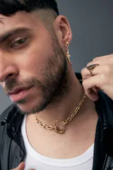 Collar de cadena gruesa dorada con eslabones rectangulares y un dije circular con anillos colgantes.