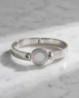 Esclava rígida de acero inoxidable con diseño circular central que presenta nácar en una cara y ónix en la otra, rodeado por una inscripción de números romanos.
