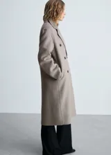 Abrigo largo de diseño oversize confeccionado en tejido con mezcla de lana. Presenta cuello con solapas de muesca, cierre frontal de doble botonadura y hombros caídos. Cuenta con dos bolsillos laterales y abertura posterior en el bajo.