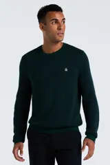 Sweater de punto color verde oscuro, con cuello redondo, mangas largas y puños acanalados. Presenta el logo de la marca bordado en el pecho.