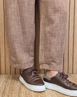 Pantalón de lino color marrón con corte barrel, tiro medio, cintura elástica con cordón de ajuste y bolsillos laterales.
