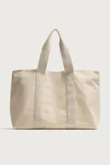 Bolso tipo shopper de tejido de algodón color beige, con doble asa de mano y cierre magnético.