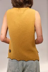 Chaleco de punto de lambswool color mostaza, sin mangas, con cuello redondo y diseño de ochos en la parte delantera.