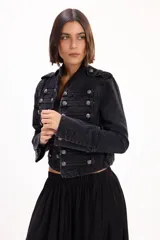Chaqueta de jean estilo napoleónico color negro, con cuello mao, hombreras y filas dobles de botones metálicos grabados.