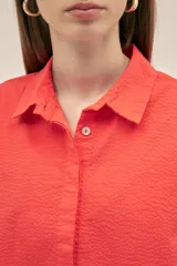 Camisa color coral de tejido seersucker texturizado, con cuello camisero, manga corta y cierre frontal con botones nacarados.