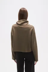 Buzo de cuello alto tipo polera, color verde oliva, con corte holgado, mangas largas y un bolsillo frontal aplicado en el pecho.