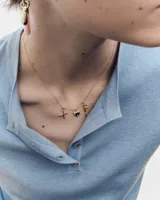 Dije en forma de corazón de metal dorado con la inscripción "mom" grabada y dos circonias incrustadas.