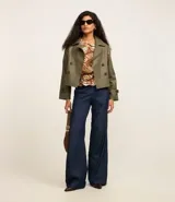 Trench coat de poliuretano color verde militar, con cuello de solapa, diseño cruzado y cierre frontal de doble botonadura.