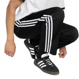 Pantalon deportivo Adidas modelo Firebird, color negro, con las icónicas tres tiras blancas laterales y logo del trébol bordado en la pierna. Presenta cintura elástica y corte recto.