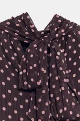 Blusa de cuello subido con diseño de lunares, manga larga abullonada con puños elásticos y forro interior.