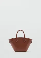 Cartera de mano color marrón, de diseño estructurado tipo trapecio, con doble asa corta y detalles de correas laterales ajustables con hebilla.