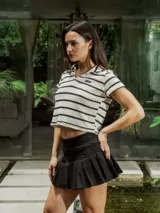 Chomba crop de tejido de punto abierto con diseño a rayas horizontales en color crudo y negro, cuello polo y bordado en el frente.
