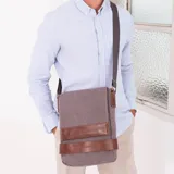 Morral versátil de tela canvas gris con detalles en cuero sintético marrón. Cuenta con tapa frontal con broches magnéticos, bolsillo tipo guantera bajo la tapa, división interna desmontable con velcro y correa larga regulable.