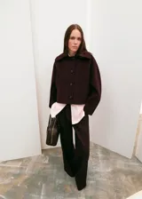 Chaqueta de lana y mezcla sintética color bordó, con cuello amplio, cierre frontal de botones y mangas largas holgadas.