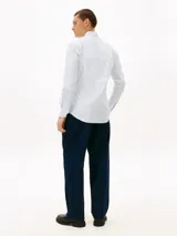Camisa de Tommy Hilfiger confeccionada en popelín de puro algodón regenerativo con diseño de rayas bengal en tonos celeste y blanco. Cuenta con cuello camisero, cierre frontal de botones y el logo de la marca bordado en el pecho.