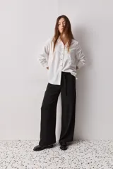 Pantalón wide leg de color negro, con cintura de tiro alto, lazo ajustable y caída fluida.