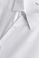 Camisa de corte slim fit confeccionada en tejido de algodón con textura. Presenta cuello italiano, manga larga con puños abotonados y cierre frontal mediante botonadura.