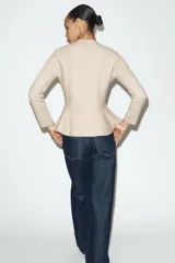 Chaqueta entallada de punto con escote en pico y manga larga. Presenta un diseño con bajo en evasé tipo peplum y cierre frontal con botones forrados a tono.