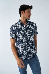 Camisa de manga corta con estampado botánico de hojas en tonos azul y blanco. Presenta cuello clásico, cierre frontal abotonado y corte slim.
