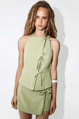 Falda pantalón de tiro medio en color verde claro, confeccionada con mezcla de lino. Cuenta con diseño cruzado en el delantero y detalle de lazada lateral.