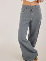 Pantalón de tiro medio alto, color gris azulado, con bolsillos delanteros y traseros. Presenta detalles de atraques y triples costuras en color amarillo.