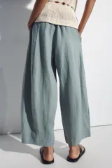 Pantalón barrel negro confeccionado en 100% lino, con tiro medio y cintura elástica fruncida. Cuenta con bolsillos laterales y falsos bolsillos de vivo en la espalda, de corte amplio y holgado.