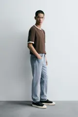 Pantalón de jean corte slim fit, color gris con efecto lavado. Presenta diseño de cinco bolsillos, cierre frontal con cremallera y botón, y tejido elástico.