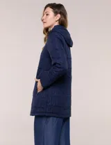 Campera larga de color azul marino con diseño capitoneado geométrico, capucha desmontable y cierre frontal completo. Cuenta con bolsillos laterales con cierre y ajuste en la cintura.