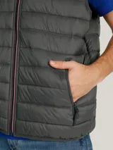 Chaleco acolchado de nailon en color gris, con cuello alto, cierre frontal de cremallera y bolsillos laterales con cierre. Presenta el logo de la marca bordado en el pecho.