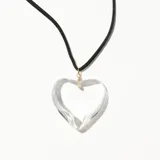 Colgante con dije de corazón transparente y cordón negro.