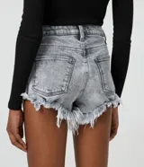 Short hot pants de jeans color gris claro con cintura alta, cierre con cremallera y botón, bolsillos y terminación deshilachada.