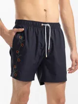 Short de baño azul marino con bordado de enredadera en la pierna izquierda. Tiene cintura elástica con cordón regulable, bolsillos laterales y trasero con cierre, y suspensor de malla fina hipoalergénico.