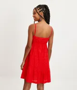 Vestido corto rojo con breteles finos ajustables, escote en pico, textura de flores y volado en el bajo.