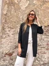 Chaqueta negra de corte abierto y diseño largo, sin cuello, con mangas tres cuartos y bolsillos frontales.