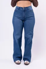 Jean de corte wide leg con tiro alto, confeccionado en denim de color azul medio. Presenta diseño de cinco bolsillos, cierre frontal con botón y cremallera, y pernera amplia y recta.