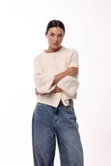 Chaqueta tejida de silueta recta con botones frontales y mangas tres cuartos terminadas en puños de piel sintética suave. Diseño versátil que permite usarla con los botones hacia adelante o hacia atrás.