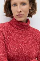 Polerón de cuello alto confeccionado en tejido buclé con textura jaspeada, de corte holgado y mangas largas con diseño raglán.