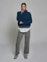 Sweater de tejido de punto grueso en color azul, con cuello alto y medio cierre frontal. Presenta detalles de rayas en contraste en los puños y el ruedo, con un diseño de corte holgado.