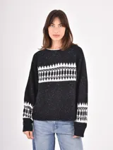 Buzo de tejido de punto en color negro con efecto jaspeado y diseño geométrico en blanco en la parte superior del pecho y en los puños. Presenta cuello redondo y mangas largas con terminaciones en tejido acanalado.