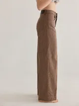 Pantalón de tiro medio alto, color beige, con bolsillos delanteros y traseros. Presenta detalles de atraques y triples costuras en color amarillo. Confeccionado en una mezcla de lino, algodón y viscosa.