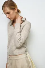 Jersey de lana 100% color beige, con cuello polo, manga larga y botones delanteros.