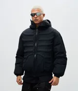 Campera puffer negra con diseño acolchado que simula una estructura de esqueleto. Cuenta con capucha, cierre frontal con cremallera, mangas largas y puños elásticos.