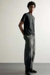 Jeans de denim de algodón color gris con efecto lavado, de corte relaxed barrel fit y tiro medio. Presenta diseño amplio con pinzas en las rodillas y costuras curvas, cierre frontal con botones y cinco bolsillos tradicionales.