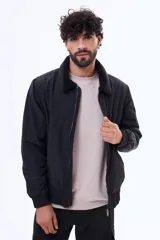 Campera de nylon color negro con cierre frontal, puños y ruedo elásticos, y cuello con forro de corderito sintético.