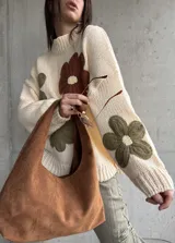Sweater de tejido de punto color natural, con diseño de flores grandes aplicadas en tonos marrón y verde oliva. Presenta cuello redondo, mangas largas y corte holgado.