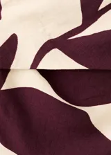 Monopieza sin mangas con escote palabra de honor, de corte recto y largo, con diseño estampado de hojas en tonos beige y bordó. Cuenta con cierre de cremallera en la parte posterior y forro interior.