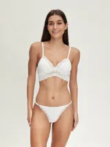 Conjunto de ropa interior blanco, compuesto por un bralette con encaje en el escote y una tanga con detalles de encaje.
